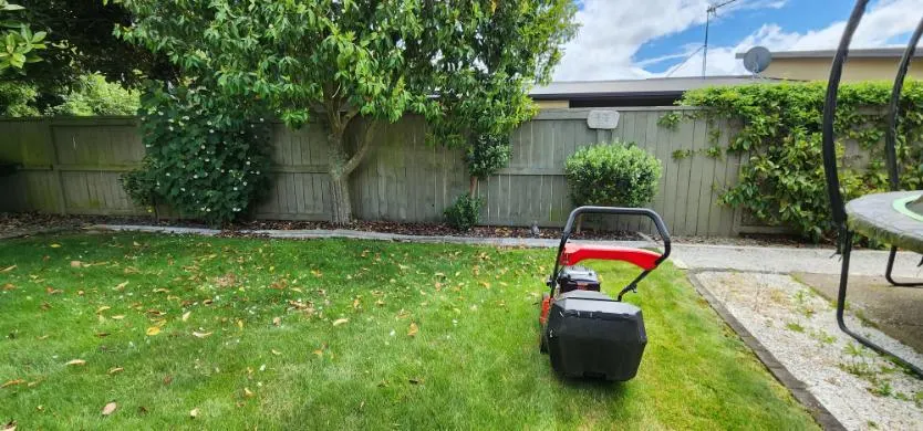 Back lawn with a neat stone-edged garden bed along the fence in Forrest Hill, Auckland