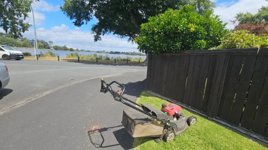 Lawn mowed beside a black fence with the lake in the background, North Shore, Auckland