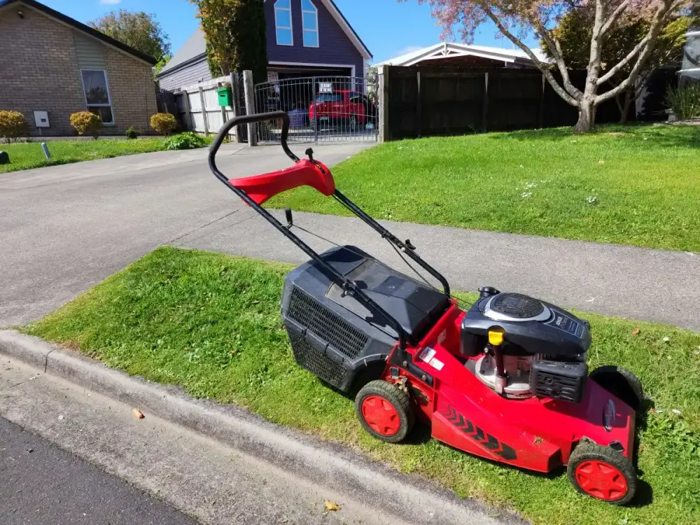 Red mower on a freshly cut front lawn in a North Shore street, Auckland